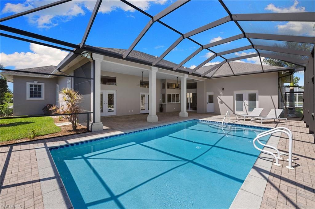Screened-in pool area featuring a rectangular swimming pool with integrated steps, surrounded by a paver deck
