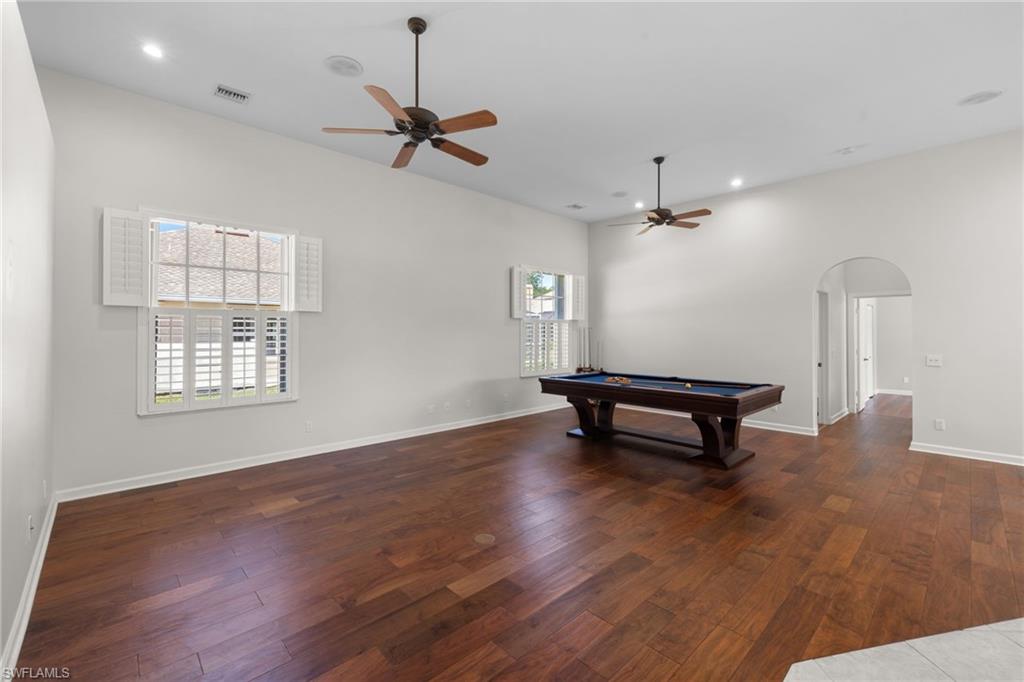 Spacious room featuring rich wood-finish flooring, high vaulted ceilings, and recessed lighting