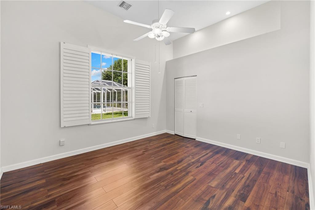 Bedroom #2, featuring bright interior space, window with louvered shutters, wood-finish flooring, and a ceiling fan