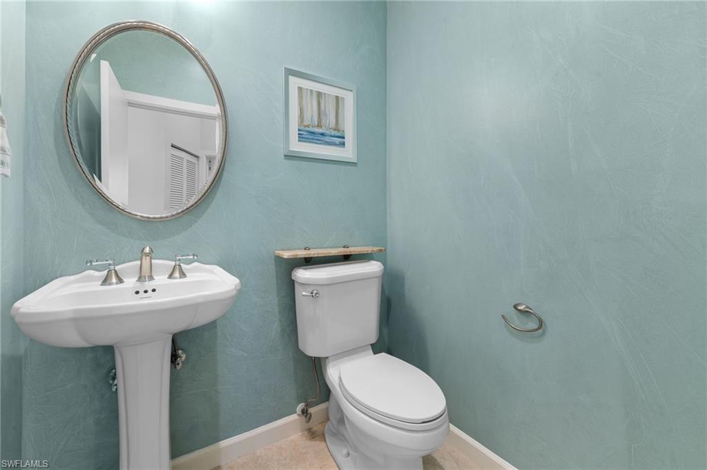 Half bathroom #3 featuring a pedestal sink, brushed nickel faucet, oval mirror, and light blue textured walls