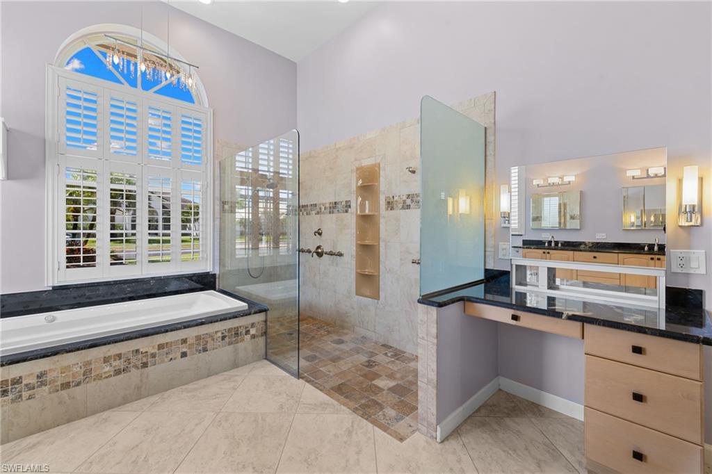 Primary bathroom #1 featuring a built-in soaking tub with a dark stone surround and decorative tile accent