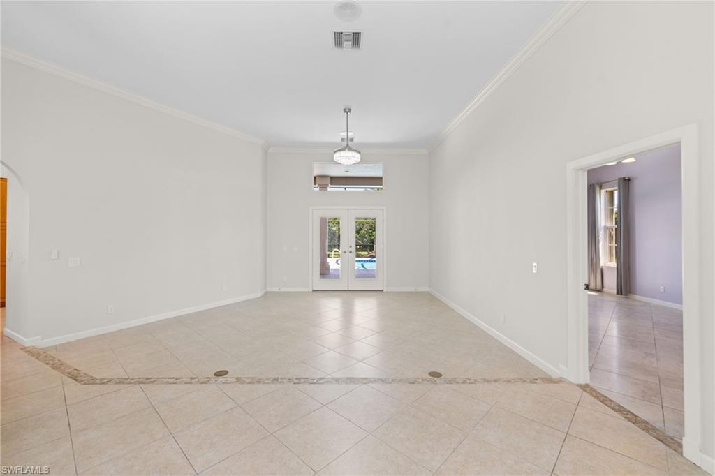 Spacious interior featuring tile flooring with decorative inlay, French doors, transom window, and crown molding