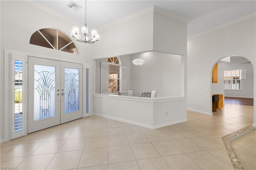 Spacious entryway featuring double-door entry with decorative glass, an arched transom window, and tile flooring