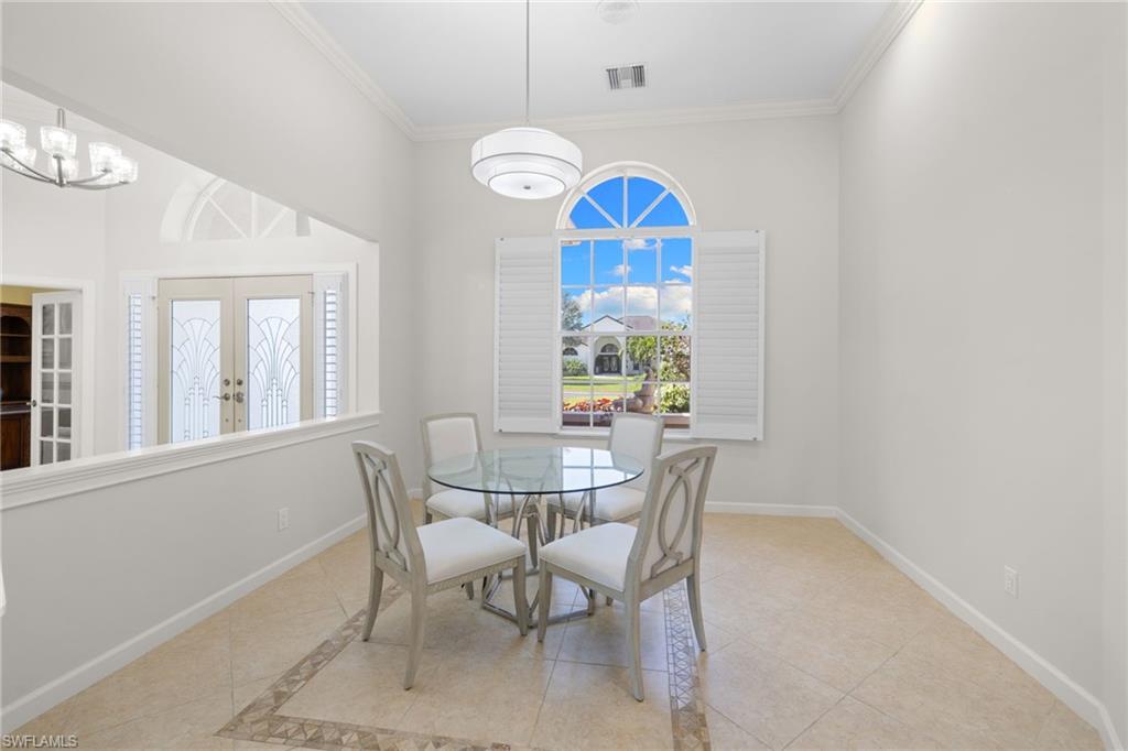 Dining area featuring a large arched window with plantation shutters, a contemporary pendant light fixture, and tile flooring with decorative inlay