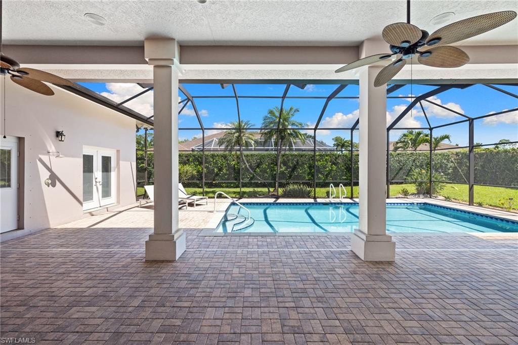 Expansive screened lanai featuring a swimming pool, textured paver patio, and ceiling fans