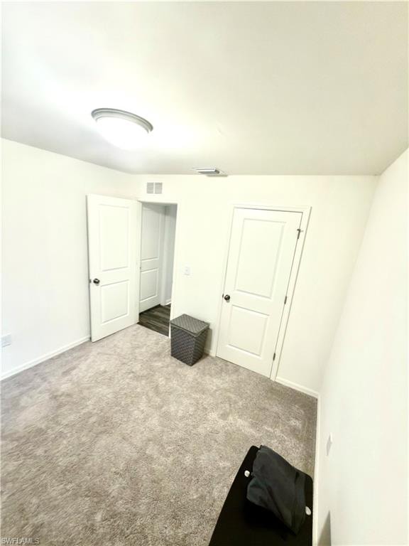 Spacious room featuring light gray carpet flooring, white walls, and a contemporary ceiling light fixture