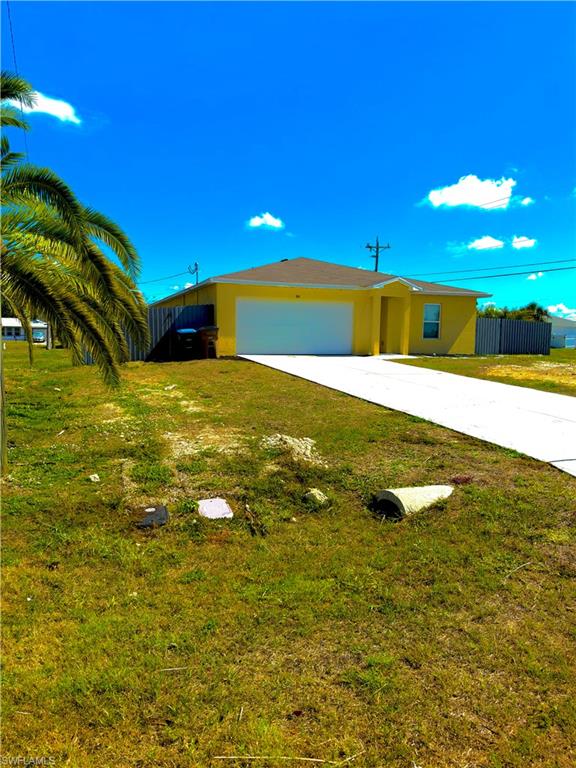 Yellow stucco exterior with a white garage door, asphalt shingle roof, and a concrete driveway