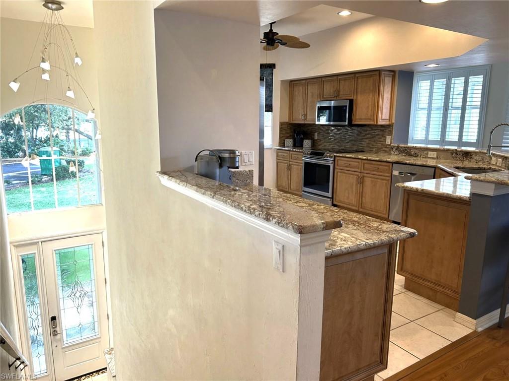 Kitchen featuring a peninsula, light granite counters, wood finish cabinets, stainless steel appliances, and backsplash