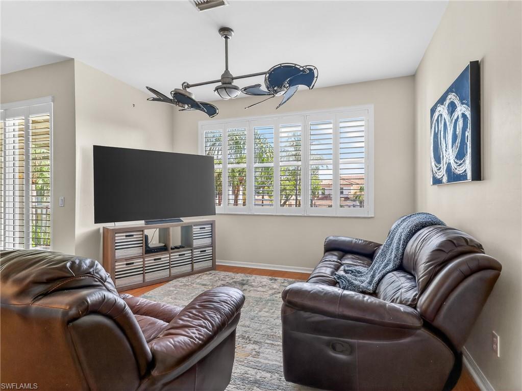 Living room with a ceiling fan, healthy amount of natural light, and wood finished floors