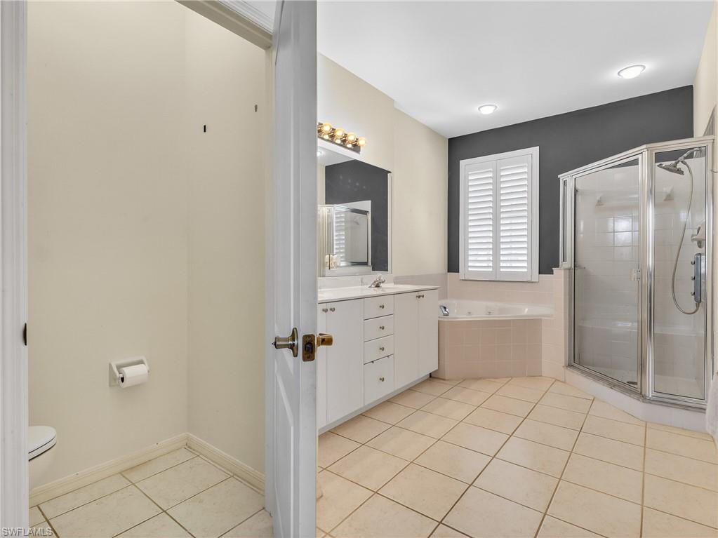 Bathroom featuring vanity, light tile patterned floors, a stall shower, and a bath