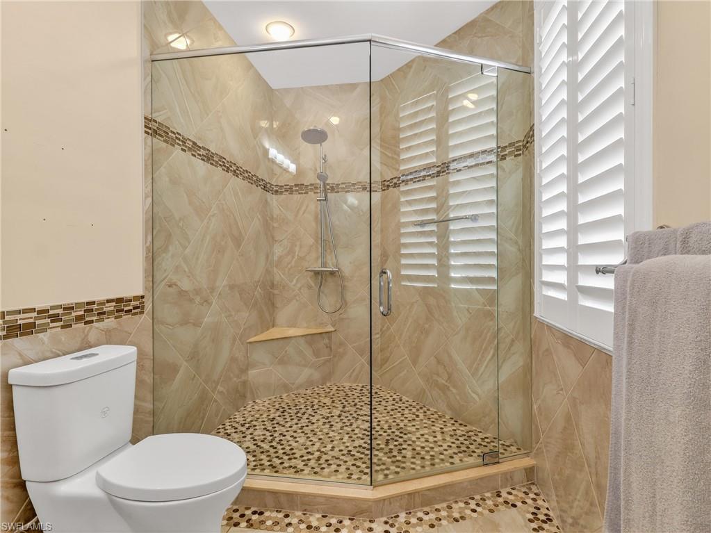 Full bathroom with a stall shower and tile walls