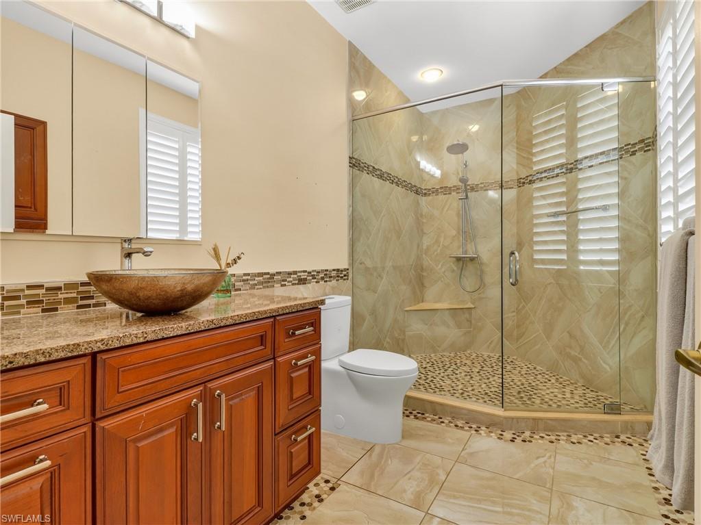 Bathroom with vanity, a stall shower, light tile patterned flooring, and tile walls
