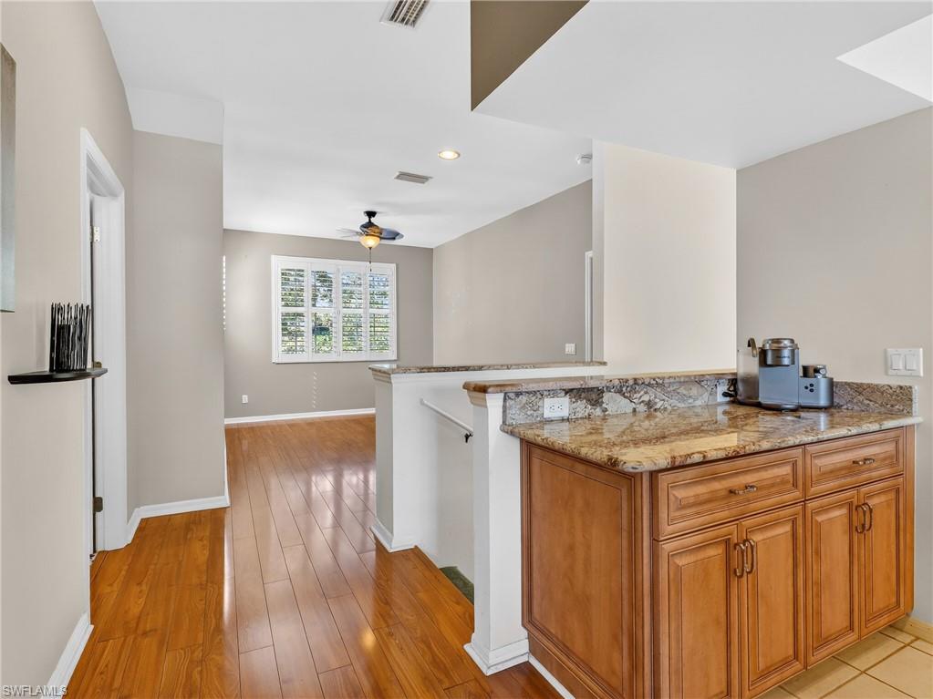 Kitchen with wood finish cabinets, light stone counters, light wood-style flooring, recessed lighting, and a ceiling fan
