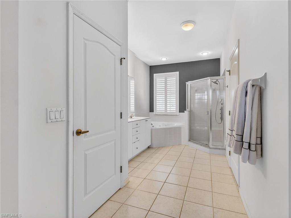 Full bathroom with a shower stall, light tile patterned floors, a garden tub, and vanity