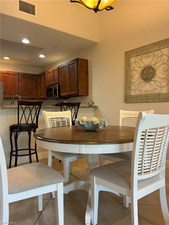 Kitchen and dining area featuring warm wood cabinetry, a granite countertop peninsula, and recessed lighting