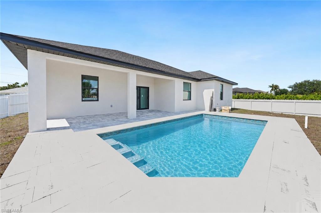 Rectangular swimming pool featuring integrated steps and a surrounding paved deck