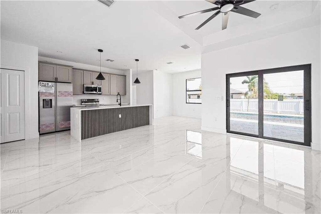 Open-concept living area featuring large format polished tile flooring and a kitchen island with a slatted wood-finish panel