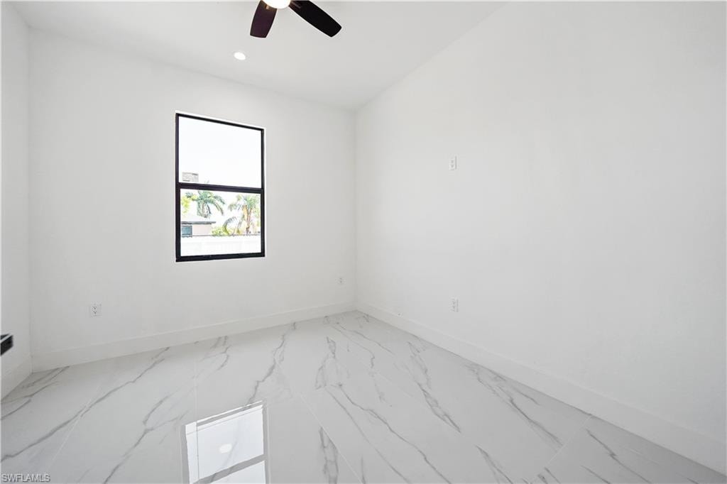 Spacious room featuring white walls, white baseboards, and large-format tile flooring with a marble-effect pattern