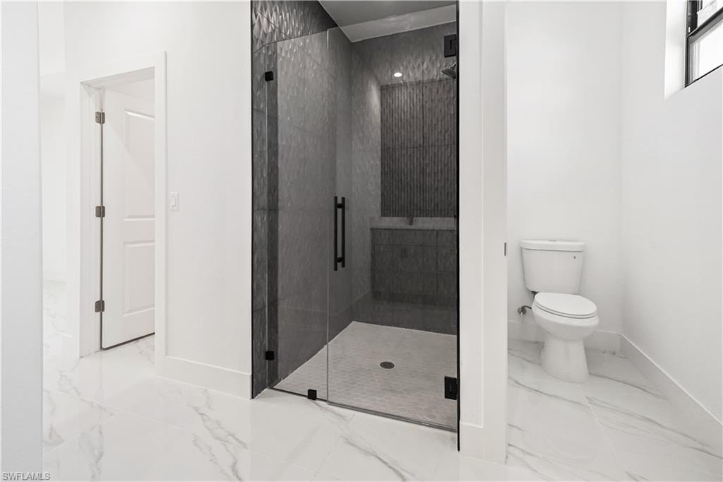 Walk-in shower with dark textured wall tile and a glass enclosure with matte black hardware