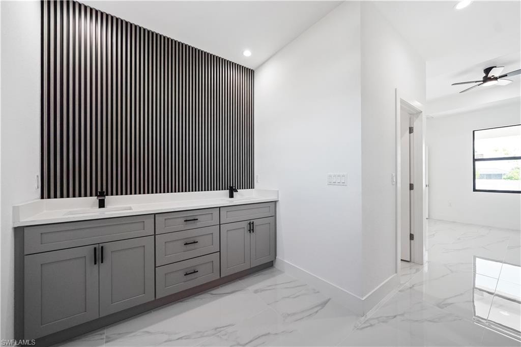 Dual basin vanity with a decorative slatted accent wall, quartz countertop, and matte black fixtures