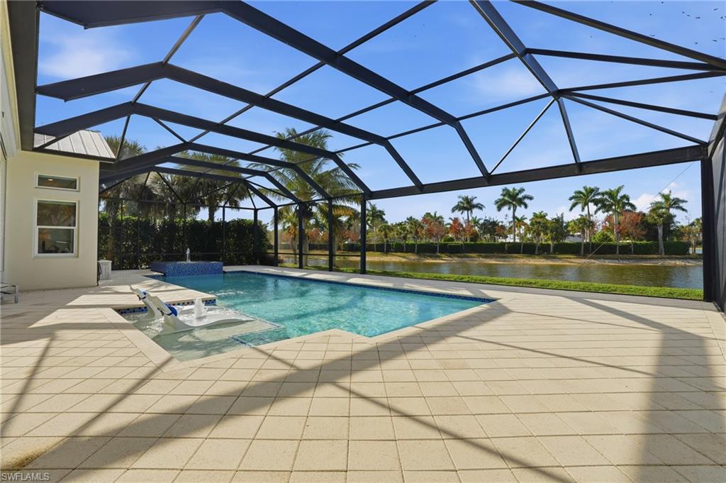 Screened lanai featuring a swimming pool, integrated spa, and spacious patio with light-toned pavers