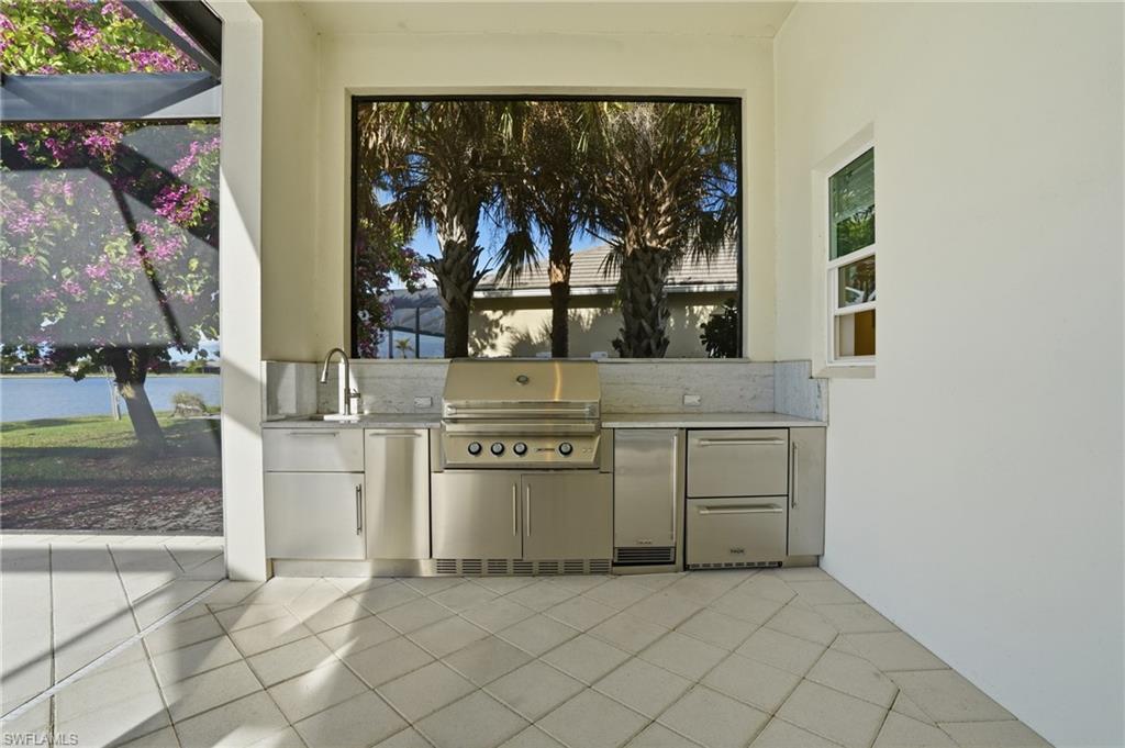 Outdoor kitchen featuring stainless steel appliances, integrated sink, and stone countertops
