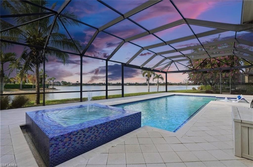 Enclosed screened lanai featuring an in-ground swimming pool, an integrated spa with a water feature, and a paved deck
