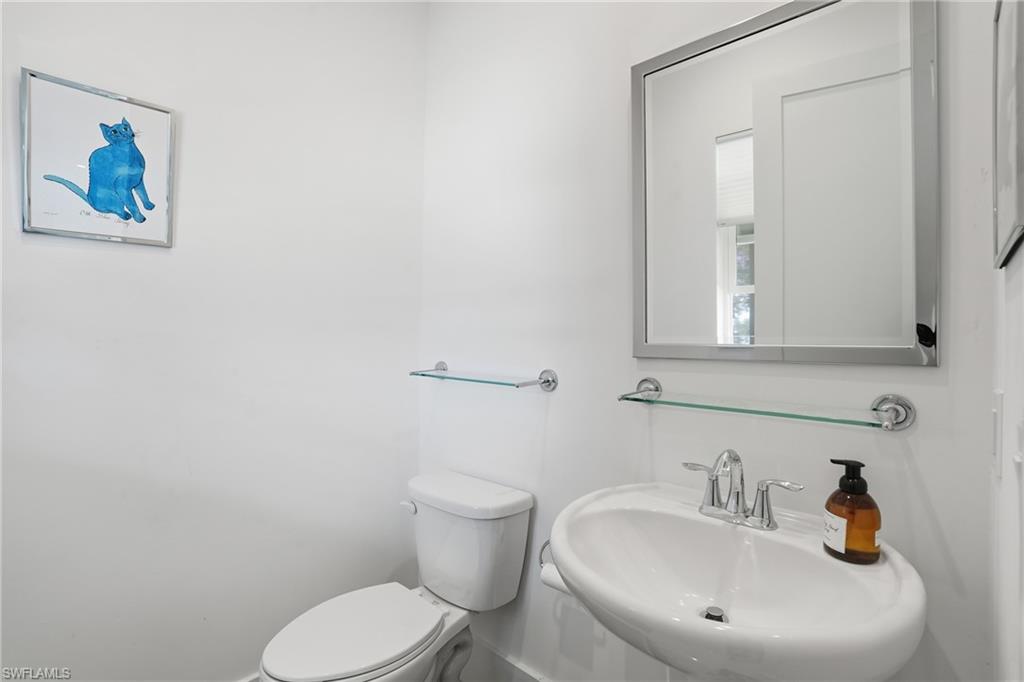 Pedestal sink featuring a chrome faucet, framed mirror, and two glass shelving units
