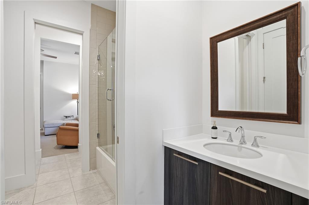 Contemporary bathroom featuring a dark wood-finish vanity with a white countertop and undermount sink, chrome faucet, and a large framed mirror