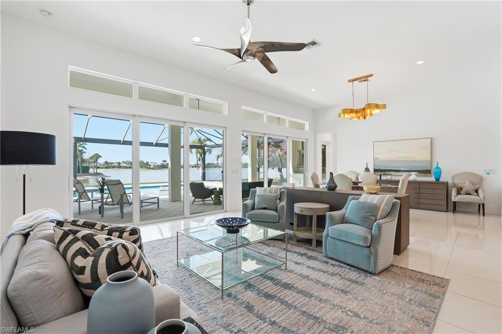 Open-concept living space featuring high ceilings, white tile flooring, and a contemporary ceiling fan