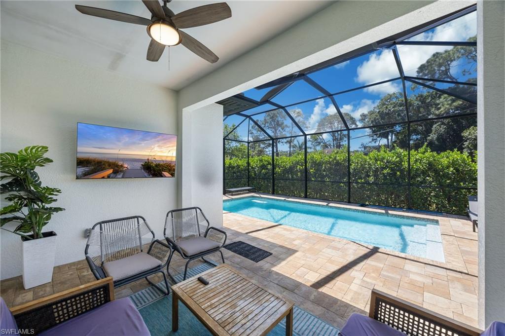 Screened-in outdoor living space featuring a ceiling fan and wall-mounted television