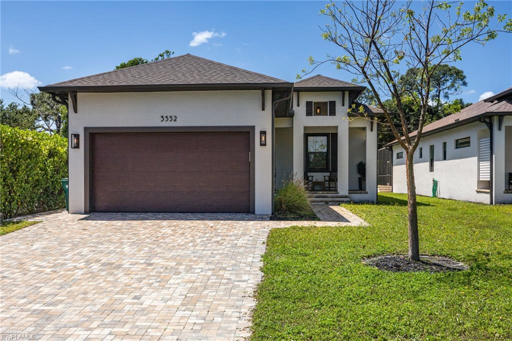 Contemporary stucco exterior with a dark brown garage door, paver driveway, and covered entry