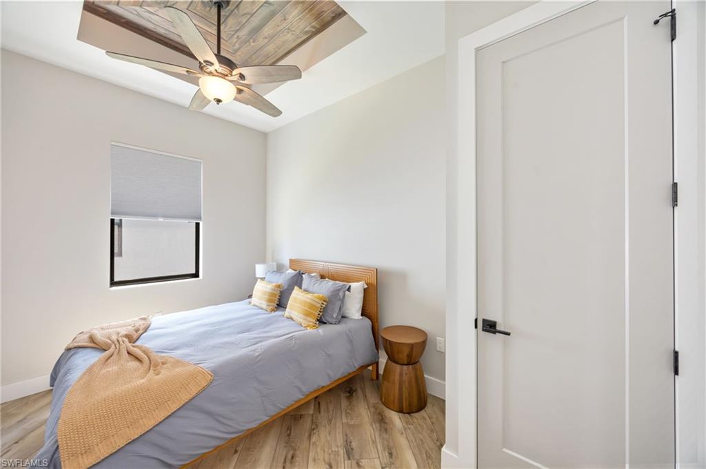 Room featuring wood-finish flooring, a white flat-panel door with matte black hardware, and a window with a roller shade