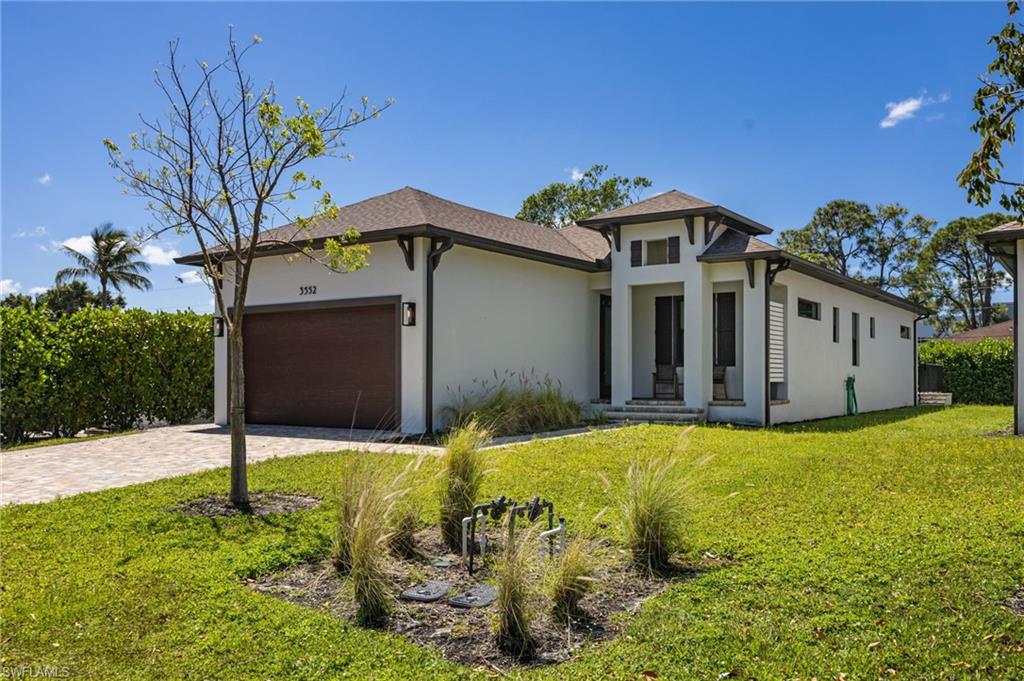 Contemporary stucco exterior with dark trim accents, a paver driveway, and a coordinating dark wood-finish garage door