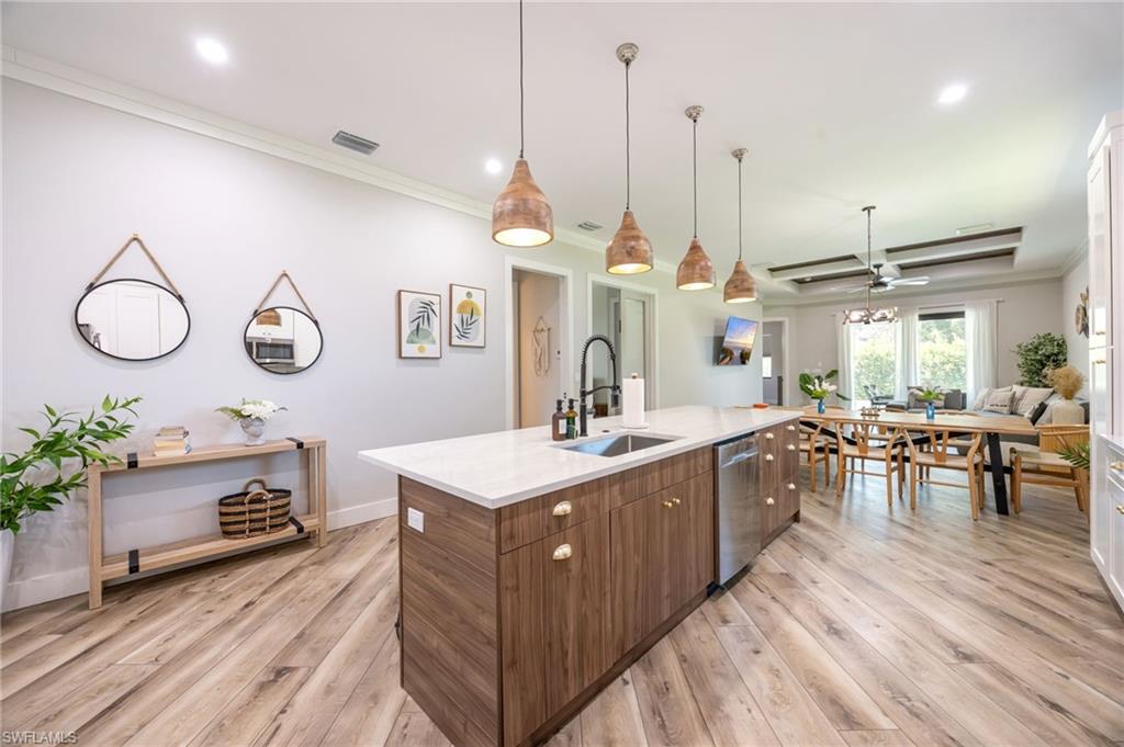 Kitchen island with wood-finish cabinetry, white countertop, and integrated stainless steel dishwasher
