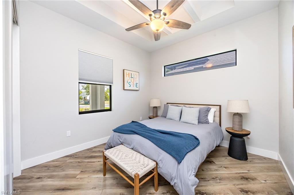 Tray ceiling with a modern ceiling fan and recessed lighting, wood-finish flooring, and white baseboards