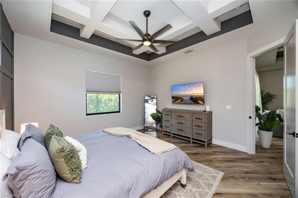 Tray ceiling with an integrated ceiling fan and recessed lighting, wood-finish flooring, and a single window with a roller shade