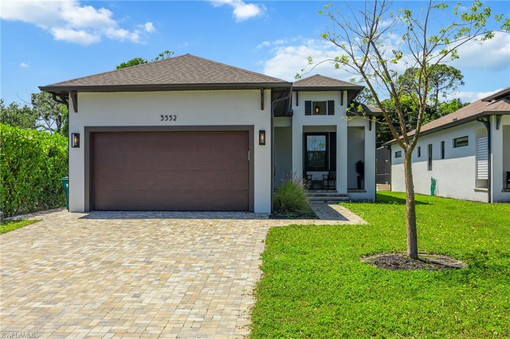Modern residential exterior featuring a brown garage door, paver driveway, and a covered entry