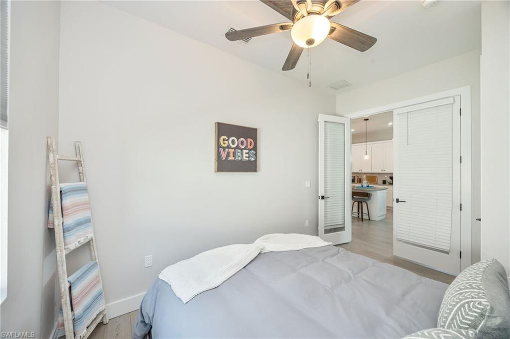 Room featuring wood-finish flooring, a ceiling fan with integrated lighting, and a white baseboard trim