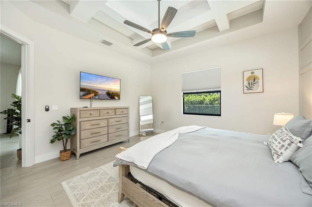 Tray ceiling with a modern ceiling fan, light wood-finish flooring, and a large window
