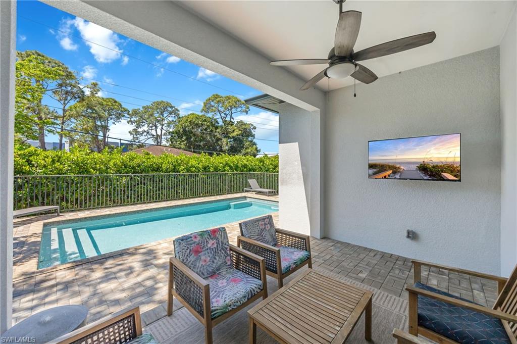 Covered patio featuring a ceiling fan, wall-mounted television, and paver flooring