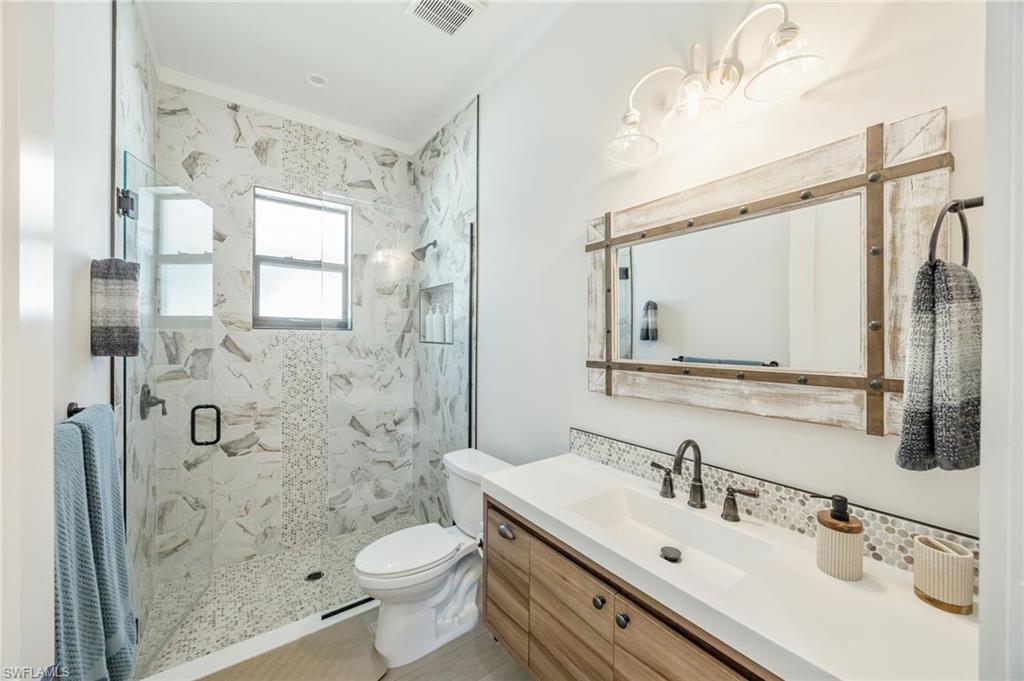 Bathroom featuring a glass-enclosed shower with mosaic tile accents and a built-in niche