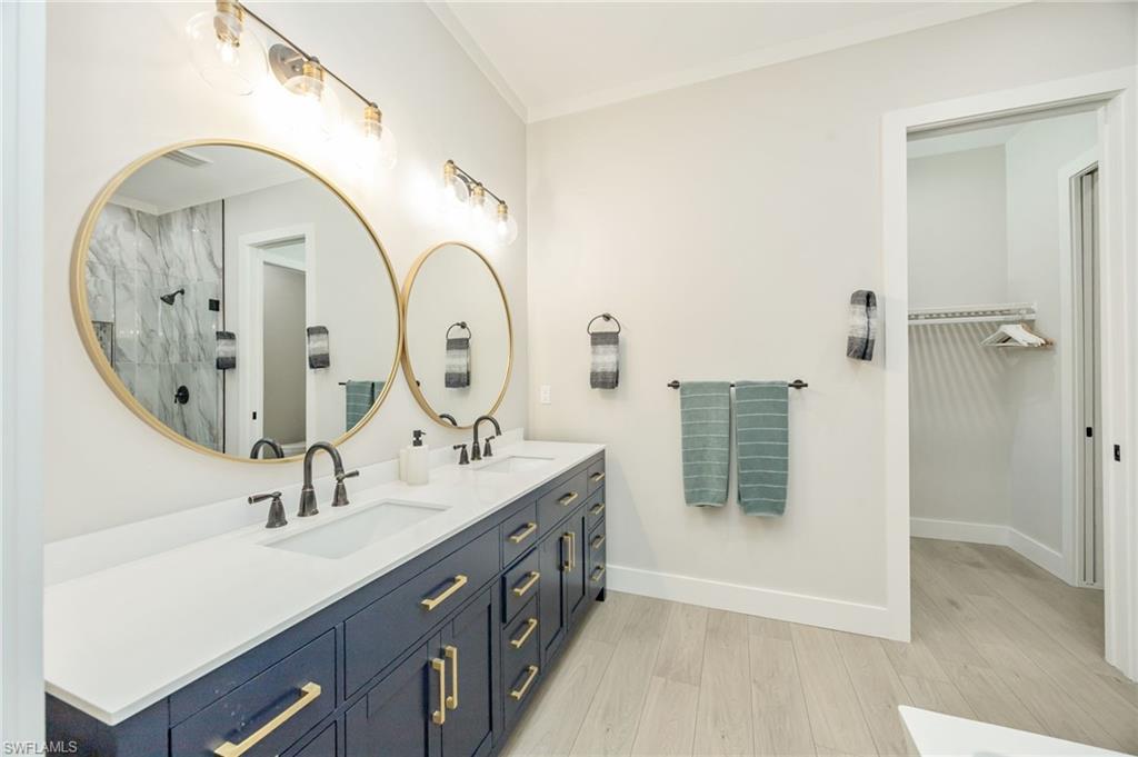 Dual vanity with quartz countertop, dark cabinetry, and gold hardware