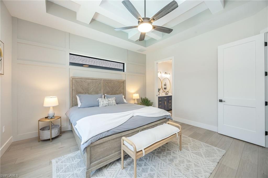 Coffered ceiling with a modern ceiling fan, plank flooring, and a decorative accent wall with a horizontal transom window