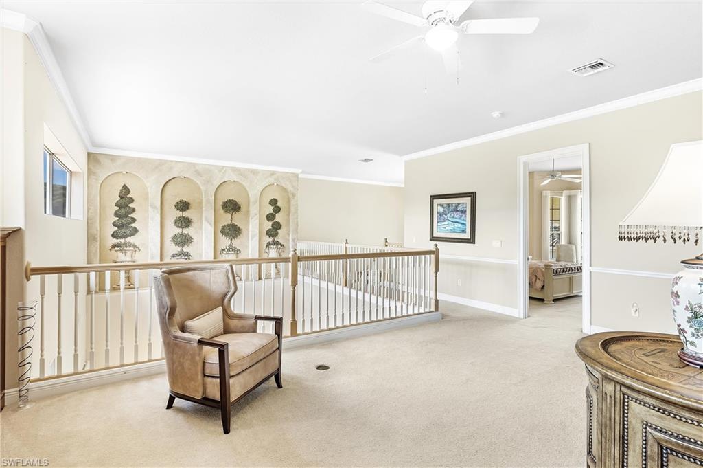 Expansive loft area featuring neutral carpeting, white baluster railings with a wood-finish handrail, and a decorative wall with arched alcoves