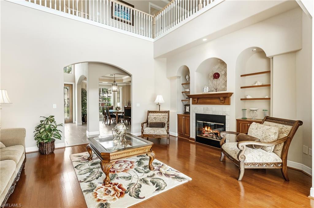 Double-height living area featuring a fireplace with a wood mantle, tile surround, and built-in cabinetry
