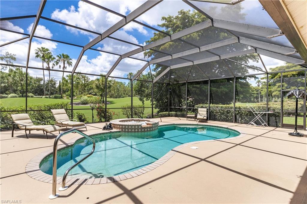 Screened outdoor living space featuring a freeform swimming pool with integrated spa