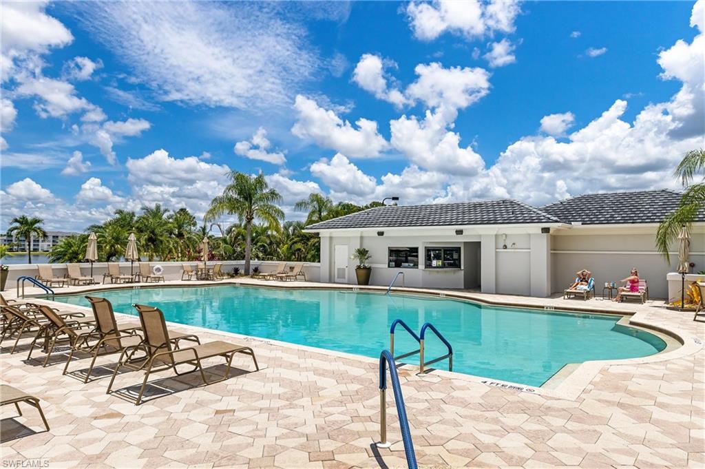 Expansive outdoor pool area with a curvilinear swimming pool, surrounded by patterned paver decking