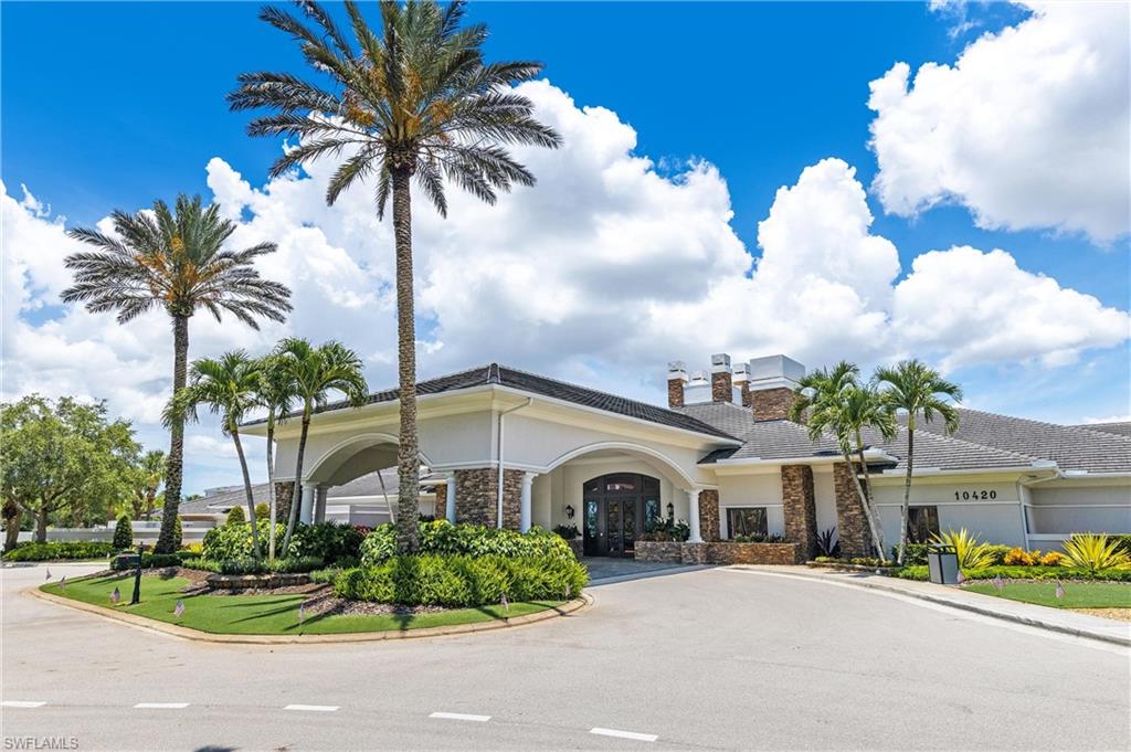 Stately  clubhousebuilding exterior featuring a covered porte-cochère entrance, stone facade accents, and a tile roof