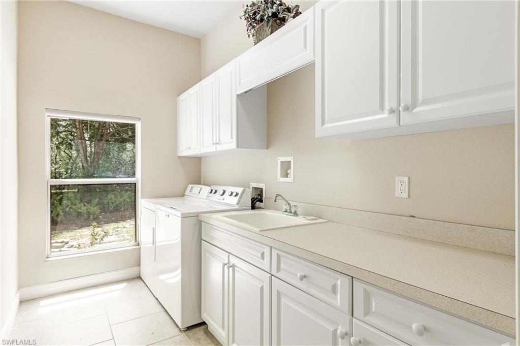 Laundry area featuring white cabinetry, a utility sink, light-toned countertops, and a window